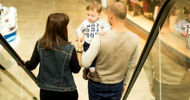 Mor, far og barn på rulletrappe i shoppingcenter